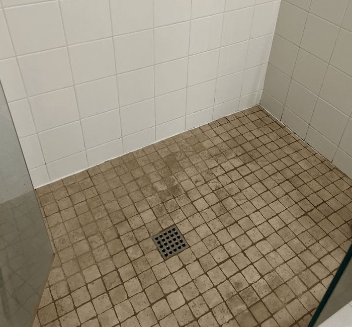 Shower corner with stained floor tile before restoration